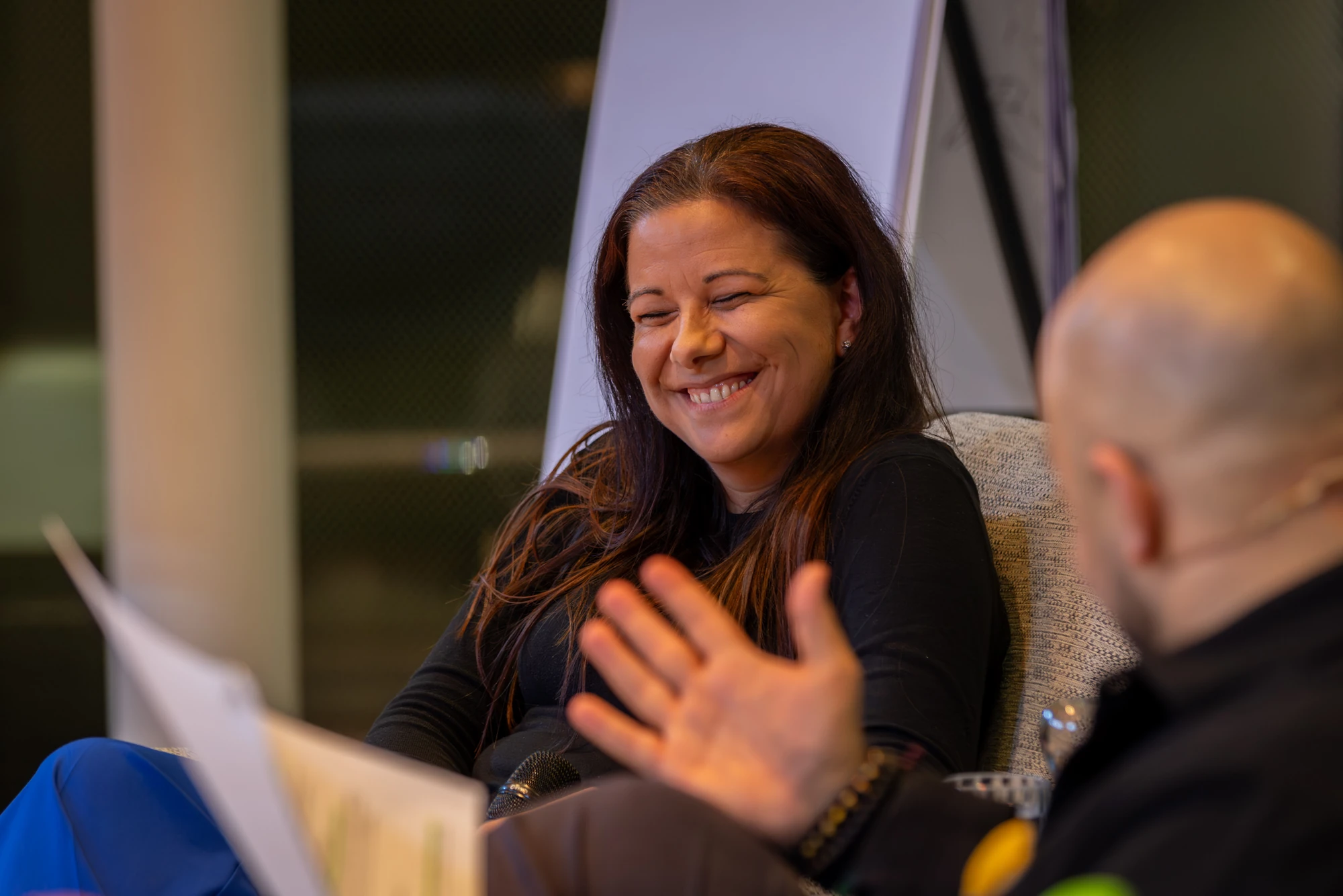 A special guest of the Future Leadership Day 2025 laughing in conversation with Ali Mahlodji, who sits opposite her in an armchair