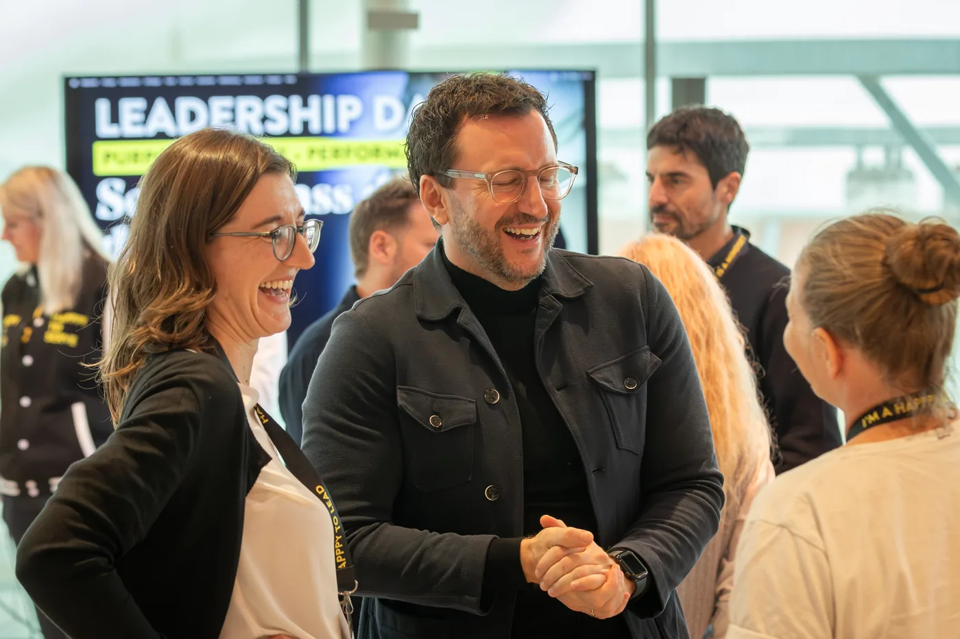 Two participants laughing together, the Leadership Day lettering behind them