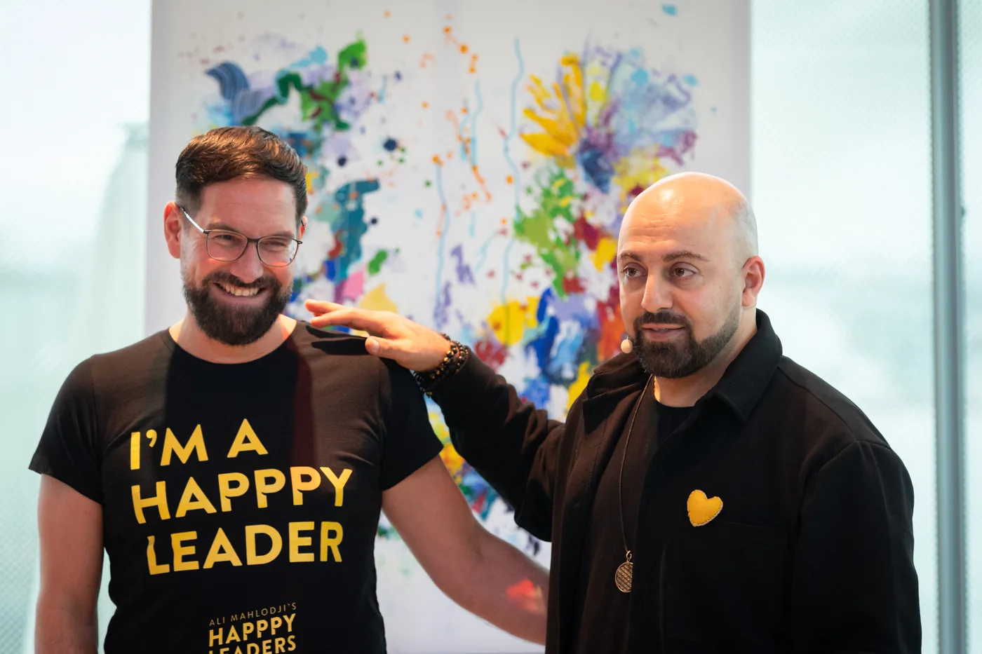 Ali Mahlodji placing his hand on the shoulder of a participant wearing an “I’m a Happpy Leader” T-shirt