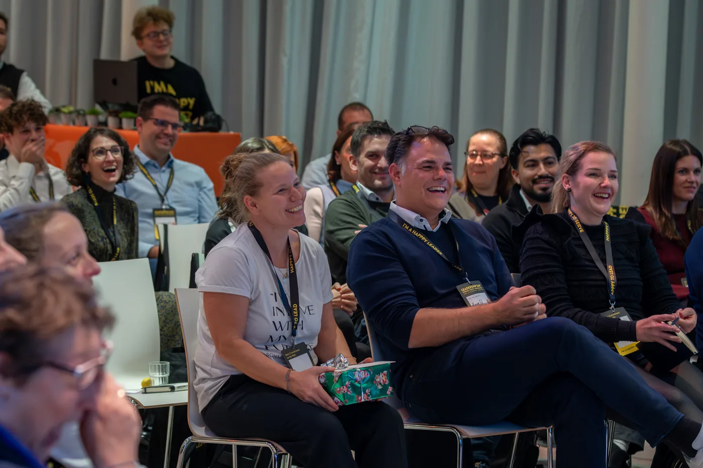 Participants in rows of chairs laughing heartily