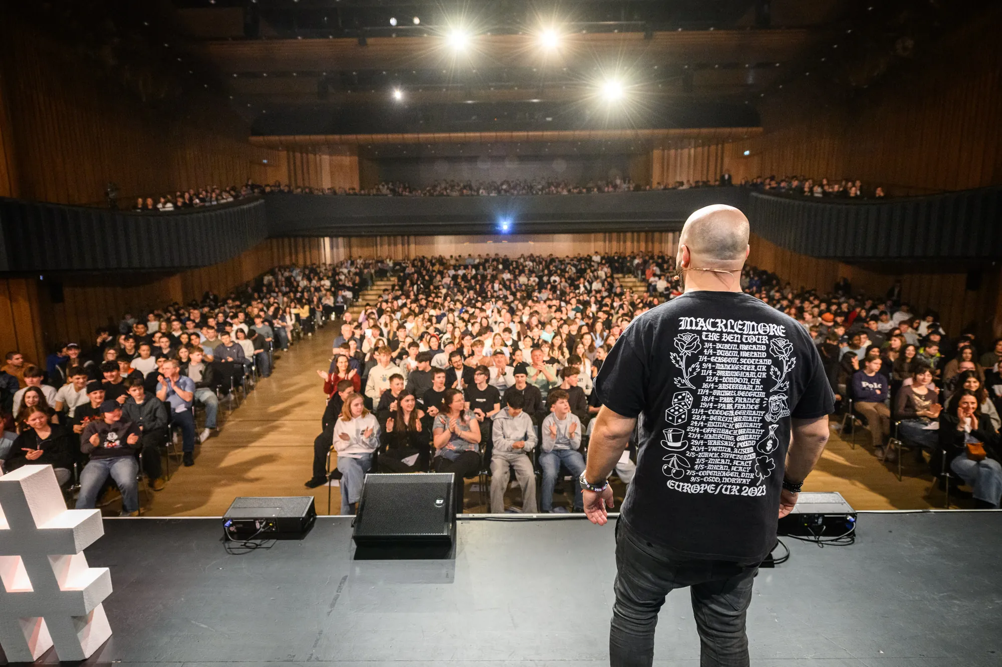 Ali Mahlodji in front of a packed concert hall of young people