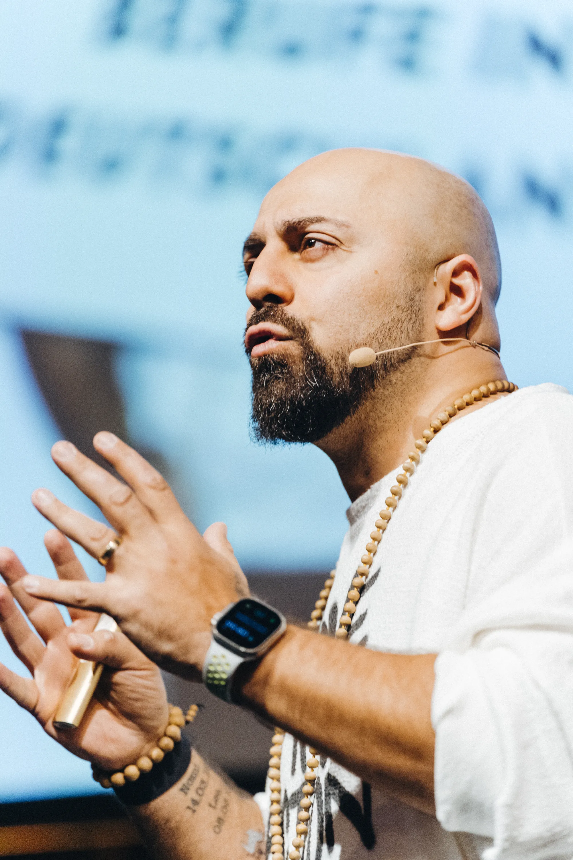 Portrait of Ali Mahlodji with headset, hands in front of his chest