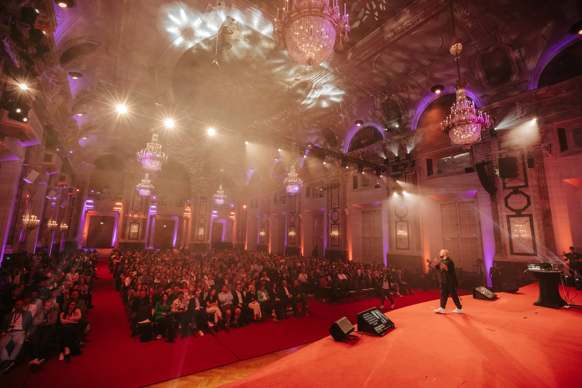 View across a full hall with chandeliers, Ali Mahlodji on the red carpet