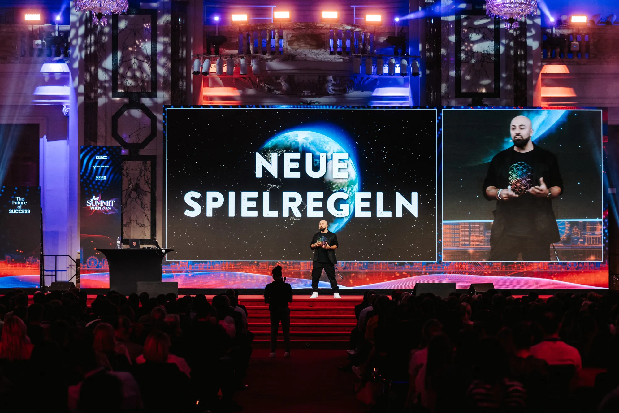 Ali Mahlodji on stage in front of the screen “Neue Spielregeln”