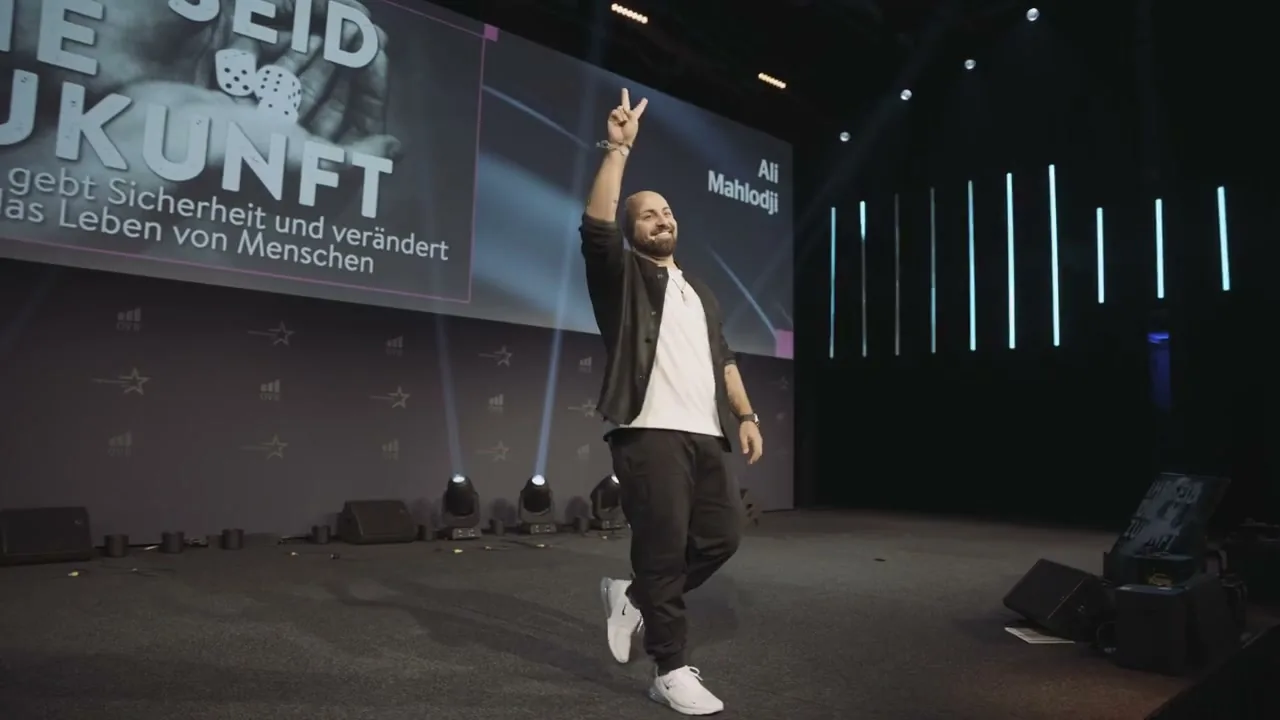 Ali Mahlodji on a big stage, arm raised, in front of the screen “You are the future”