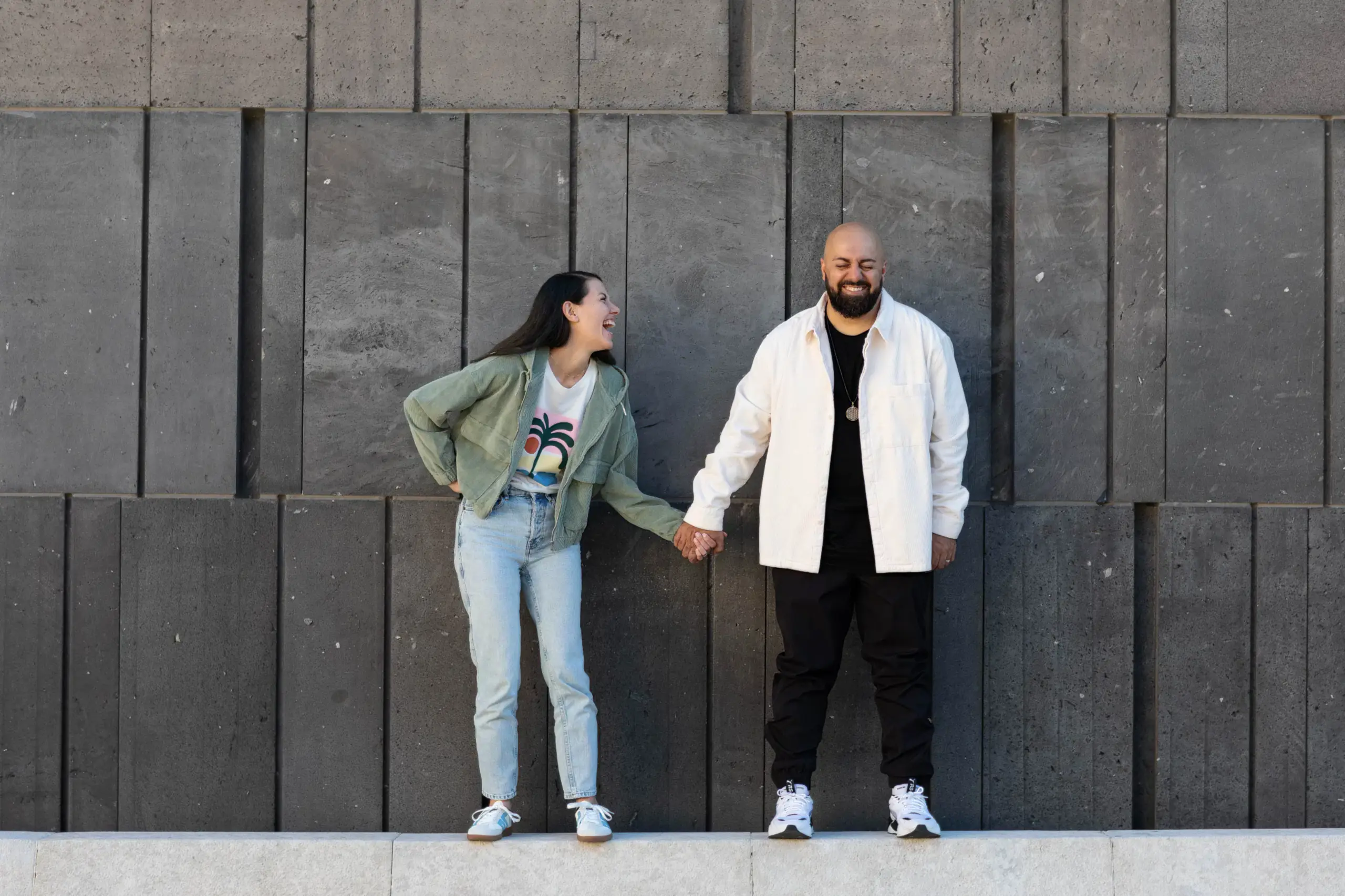 Anna und Ali Mahlodji stehen Hand in Hand vor einer dunklen Steinwand, sie lacht ihn an, er lacht mit geschlossenen Augen