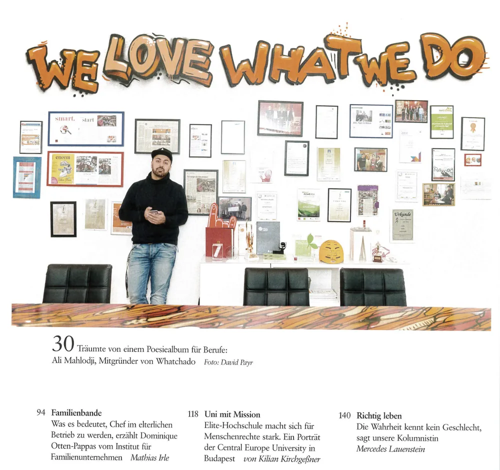 brand eins: Ali Mahlodji vor der Wand „We love what we do“