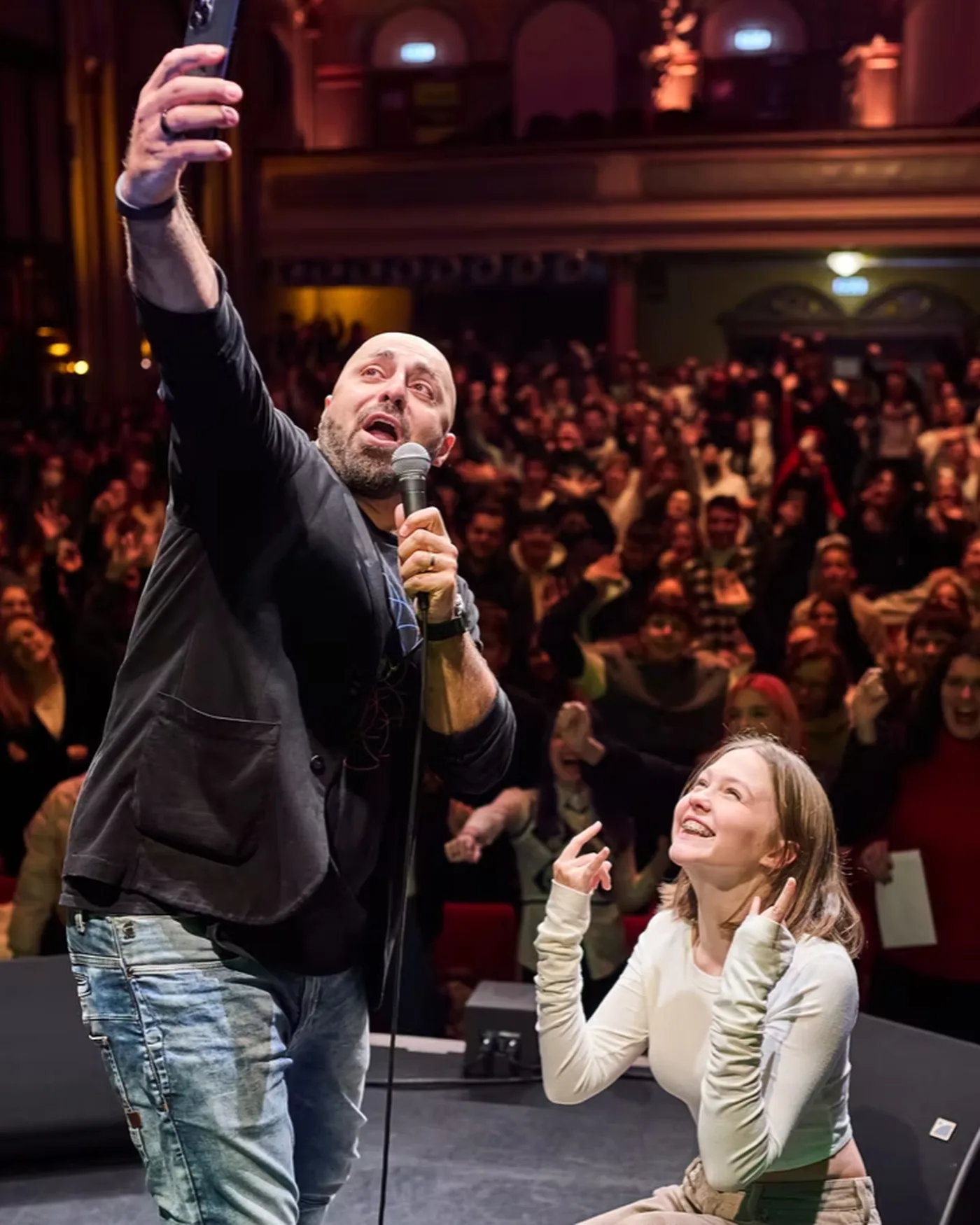 Ali Mahlodji mit einer Jugendlichen auf der futureRocka-Bühne, Selfie vor vollem Saal